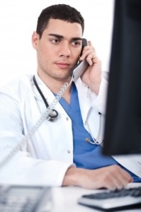 Portrait Of Male Physician Holding Receiver And Looking The Computer_by photostock